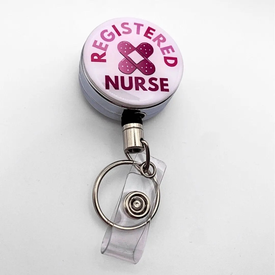 Nursing badge reel, pink writing, bandaid in the middle and white background on a metal silver reel.