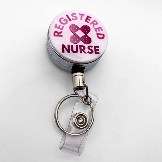 Nursing badge reel, pink writing, bandaid in the middle and white background on a metal silver reel.