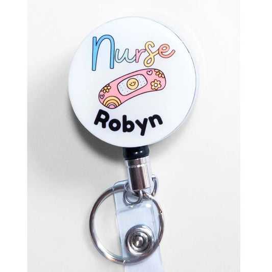 Heavy duty badge reel for nurses with a happy bandaid image and a custom name in black writing underneath.